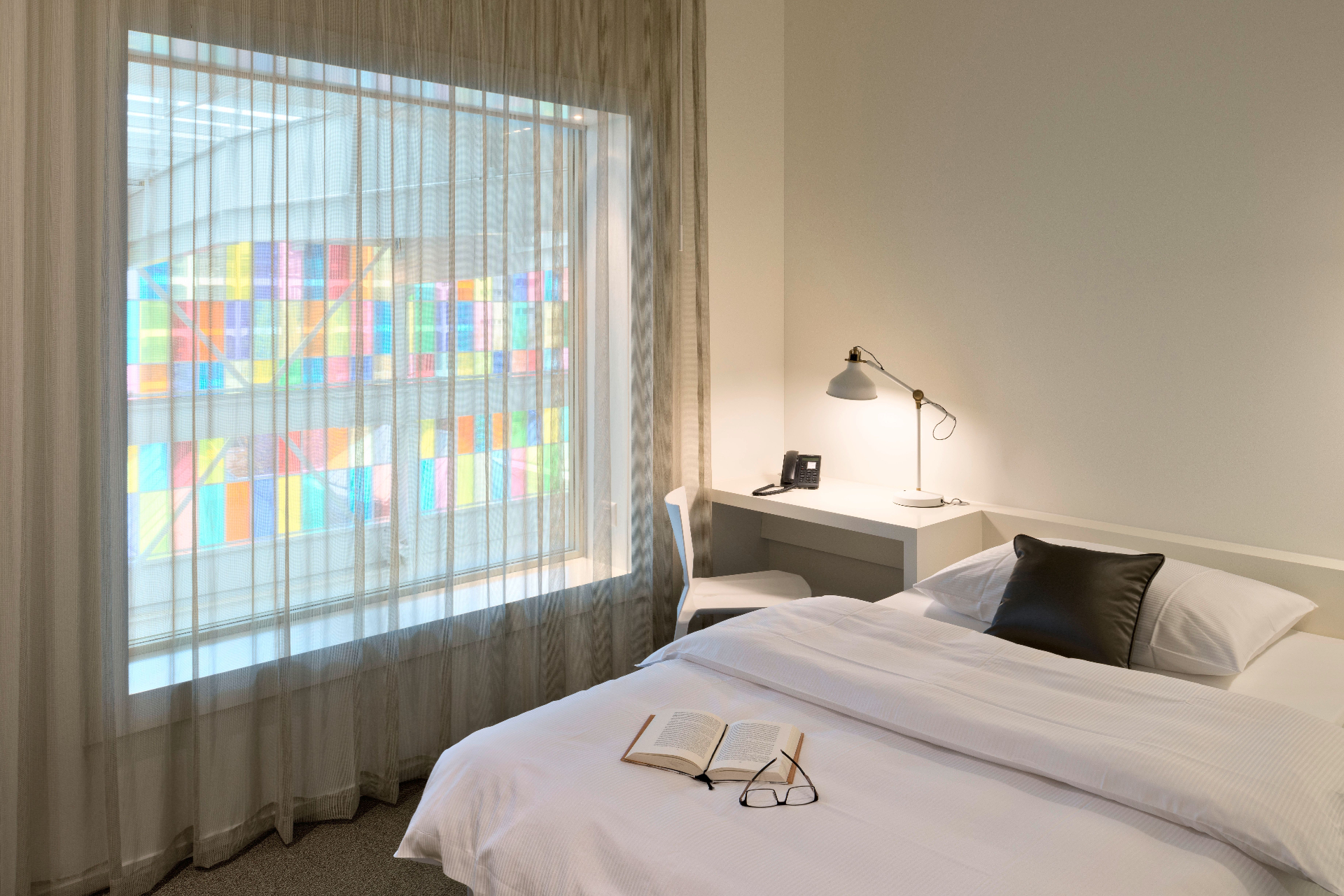 Zimmer im Trafo Hotel mit Blick auf farbige Glasfassade